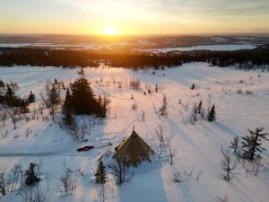 a tent in the snow with the sunset in the background at Tipi Mountain Camp in Sorsele