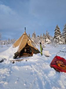 a tent in the snow next to a red bag at Tipi Mountain Camp in Sorsele