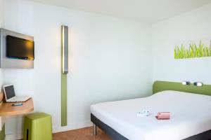 a bedroom with a bed and a tv on a wall at Hotel Ibis Budget Nancy Centre in Nancy