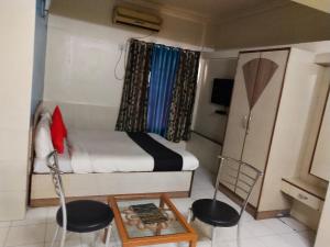a small room with a bed and two chairs and a table at Gandharva Inn in Pune +1 photo
