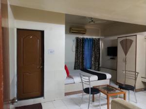 a living room with a bed and a table and chairs at Gandharva Inn in Pune
