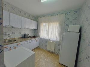 a kitchen with white cabinets and a white refrigerator at Apartamentos Turísticos Cardelemin in Caminomorisco