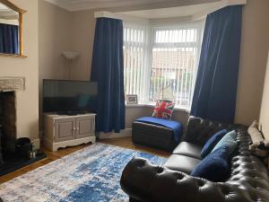 ein Wohnzimmer mit Ledercouch und Fernseher in der Unterkunft Sea Haven Northumberland in Seahouses