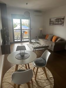 a living room with tables and chairs and a couch at Hill Apartment in Podgorica