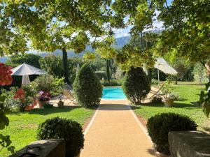 a swimming pool in a garden with trees and bushes at La Grande Maison De Nans in Nans-les-Pins