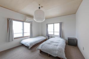 a bedroom with two beds and a tv and windows at Hostel JAQ takamatsu in Takamatsu