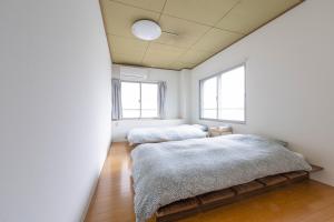 two beds in a room with two windows at Hostel JAQ takamatsu in Takamatsu