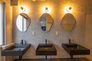 two sinks in a bathroom with two mirrors at Hostel JAQ takamatsu in Takamatsu