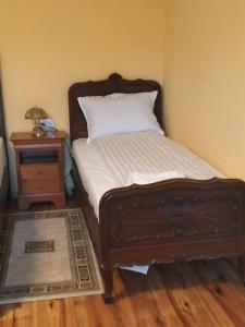 een bed met een houten frame en een nachtkastje naast een bed met bij FLH - Casa Gheti in Sighişoara