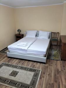 een slaapkamer met een wit bed en een stoel bij FLH - Casa Gheti in Sighişoara