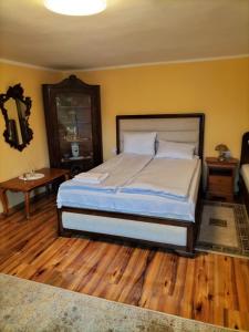 een slaapkamer met een groot bed en een houten vloer bij FLH - Casa Gheti in Sighişoara