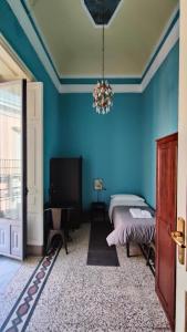 a bedroom with blue walls and a bed and a chandelier at Palazzo Arcidiacono - luxury holidays in Catania