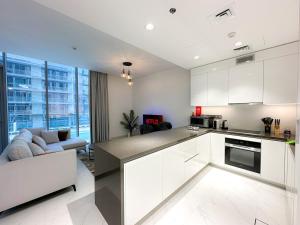 ドバイにあるLuxury 1BR with Aquatic View, District Oneの白いキャビネット付きのキッチン、リビングルーム