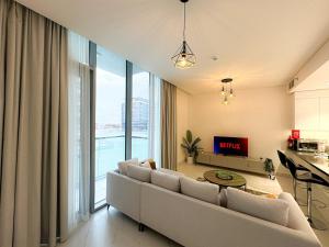 ドバイにあるLuxury 1BR with Aquatic View, District Oneのソファと大きな窓のあるリビングルーム