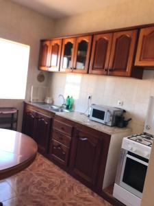 a kitchen with wooden cabinets and a sink and a microwave at Casa Andrade Delgado - Rocha Grande in Ponta do Sol