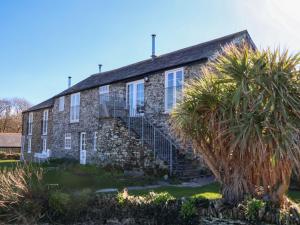 an old stone house with a staircase in front at Threshings Cottage in Tintagel