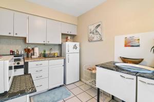 a kitchen with white cabinets and a white refrigerator at Sunny Beach Studio walk to beach in Deerfield Beach