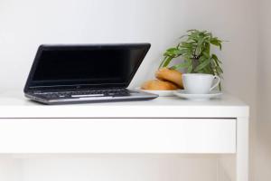 a laptop computer sitting on a white table with a plant at Apartments Kasprzaka near Metro Płocka with AC by Noclegi Renters in Warsaw +16 photos