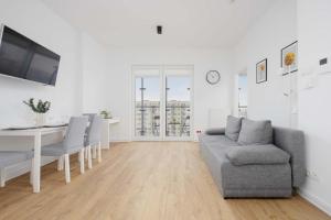 a white living room with a couch and a table at Apartments Kasprzaka near Metro Płocka with AC by Noclegi Renters in Warsaw