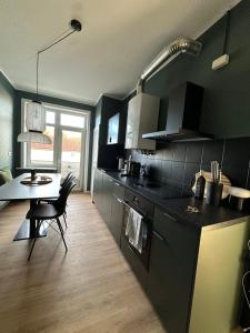eine Küche mit schwarzen Schränken, einem Tisch und einem Tisch sowie einem Esszimmer in der Unterkunft Apartment 3 Eilenriede in Hannover