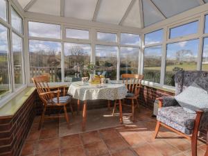 un salón acristalado con mesa, sillas y ventanas en Broadstones, en Bridport
