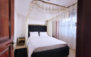 a bedroom with a large white bed and a window at Lovana Apartments and Hotel in Gulu