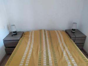 ein Bett mit einer gelben Decke und zwei Nachttischen in der Unterkunft Appartement à deux pas de la plage - Saint Pierre la Mer 6MDLM220 in Saint Pierre La Mer