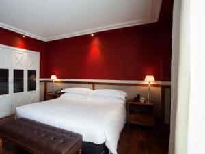 a bedroom with a large white bed with red walls at Hotel 1898 in Barcelona