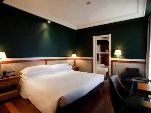 a bedroom with a white bed and a green wall at Hotel 1898 in Barcelona