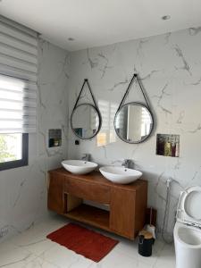 un baño con dos lavabos y dos espejos en Villa Prestige Somone, en Somone