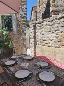 a table with plates and wine glasses on a stone wall at La Barbacane de Cascastel-des-Corbières in Cascastel-des-Corbières