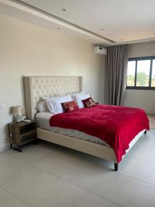 Un dormitorio con una cama grande con una manta roja. en Villa Prestige Somone, en Somone