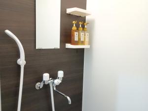 a shower with bottles of oils on a wall at 鶴の宿 那覇-国際通りまで950mの便利な立地-1棟貸切 in Naha +17 photos