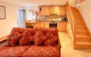 a living room with a red couch with pillows at 1 Swollowholm Cottage in Richmond