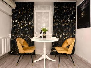 a table with chairs and a white table with wine bottles at GOLD Apartment - Tomis Nord in Constanţa