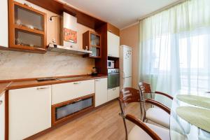エカテリンブルクにあるApartment Domashny Uyut na Belinskogo 41 Luxeの白いキャビネット、テーブルと椅子付きのキッチンが備わります。