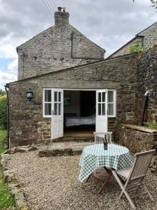 a small stone house with a bed in the doorway at 1 Swollowholm Cottage in Richmond