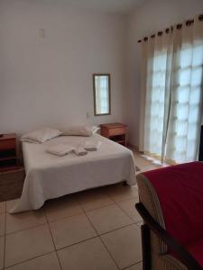 a bedroom with a large white bed and windows at pousada Boa vista in Santo Antônio do Pinhal +8 photos