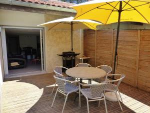 a table and chairs with a yellow umbrella on a deck at HOSSEGOR Entre lac et océan Résidence LES DUNES, villa patio pour 4 à 5 personnes in Hossegor