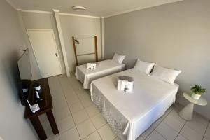 アラシャーにあるApartamento em ótima avenida de Araxáのベッド2台とテレビがあるホテルの部屋