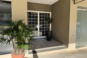 アラシャーにあるApartamento em ótima avenida de Araxáの2つの鉢植えとガラスのドアがあるロビー