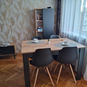 a dining room table with four chairs and a wooden table at Apartament Agnes in Gniezno