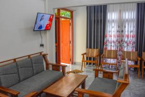 a living room with a couch and chairs and a tv at Tedro home stay in Ampitiya