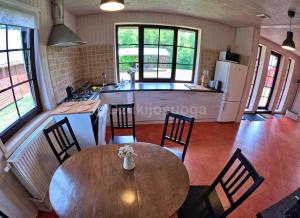 a kitchen and dining room with a wooden table and chairs at Vila Dzūkijos uoga in Viršurodukis