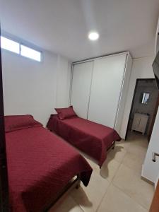 - une chambre avec 2 lits et des draps rouges dans l'établissement rocamora, à Posadas