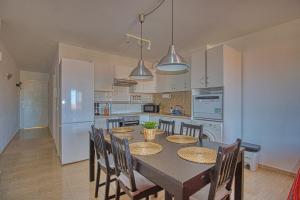 una cocina con mesa y sillas y una cocina con electrodomésticos blancos. en LANN Isis, en Arona