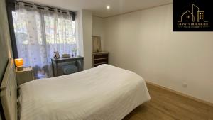 una camera da letto con un letto bianco e una finestra di Appartement 6pers - Marignier a Marignier