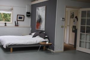 a bedroom with a large bed and a table at Atelier La Luna in Berkenwoude