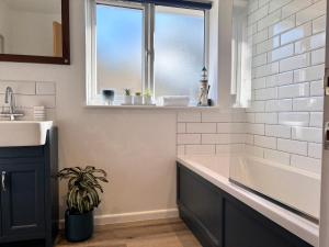 Un baño con bañera, lavabo y ventana. en Harlowe Mousehole Hideaway two bedrooms with parking, en Mousehole 14 fotos más