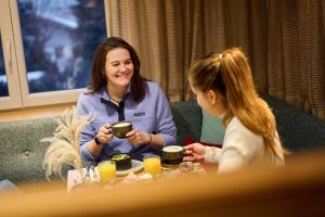 two women sitting at a table drinking coffee at Das Dorfgefühl Pension Westendorf in Westendorf